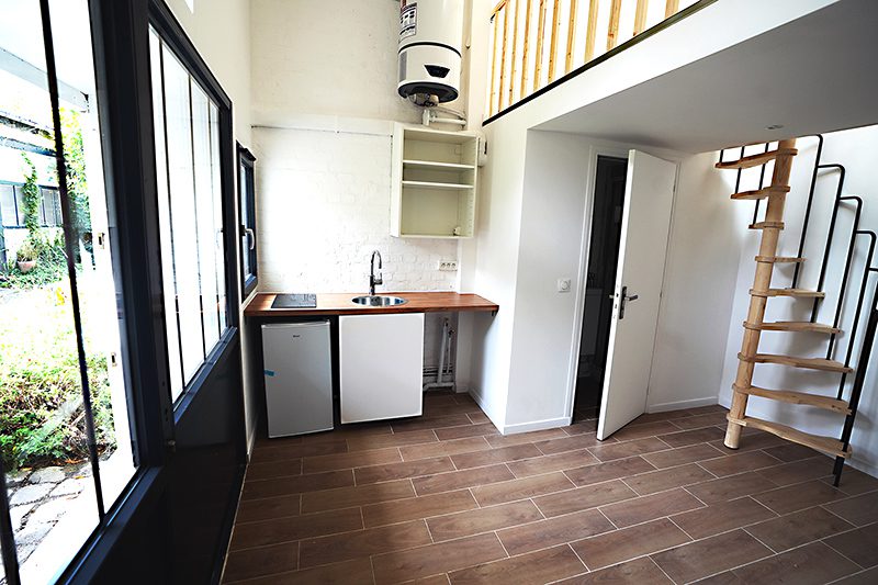 Petite cuisine moderne avec meubles intégrés, éclairée par des fenêtres en PVC à double vitrage offrant isolation thermique et acoustique.
