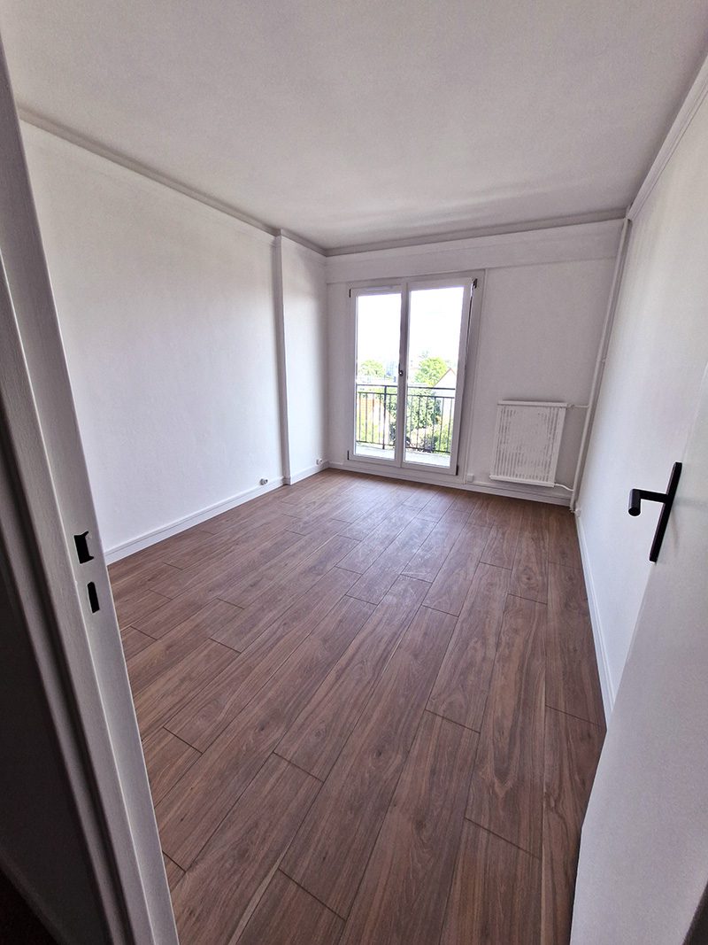 Chambre rénovée avec parquet au sol et peinture fraîche.