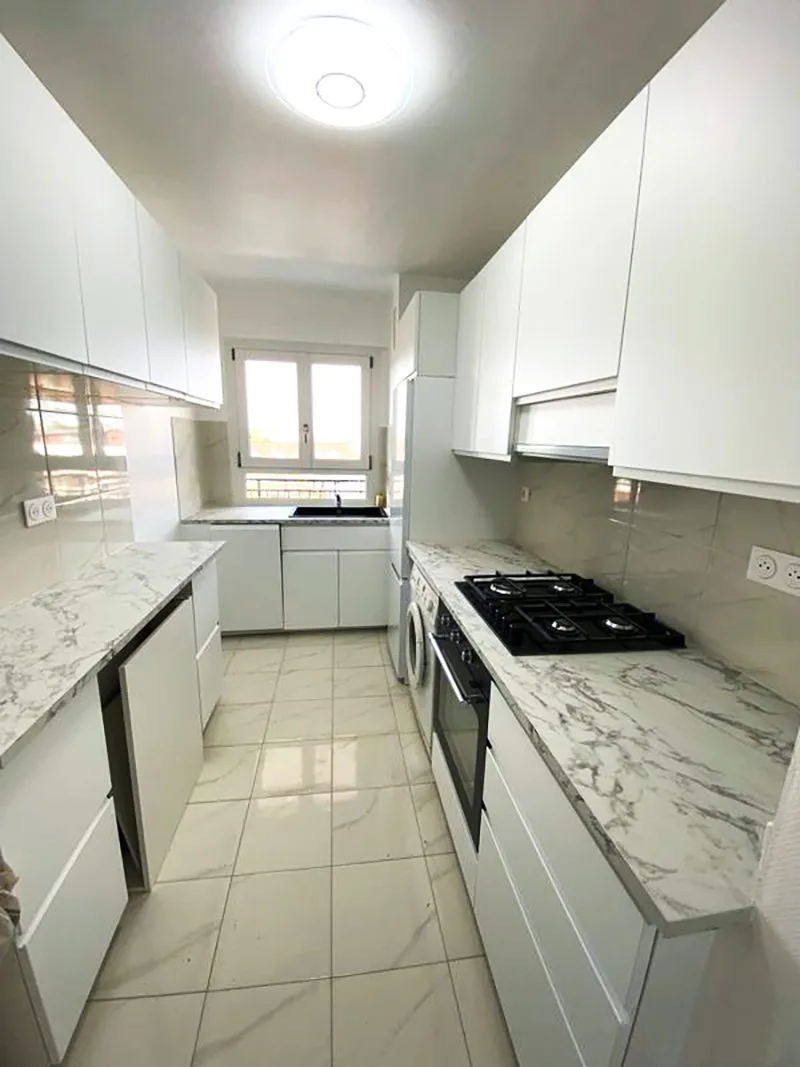 Cuisine entièrement rénovée avec meubles modernes et carrelage neuf.