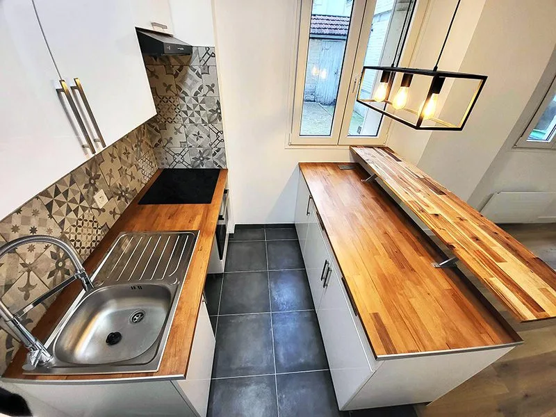 Vue après rénovation intérieure montrant une cuisine ouverte sur un grand salon lumineux.
