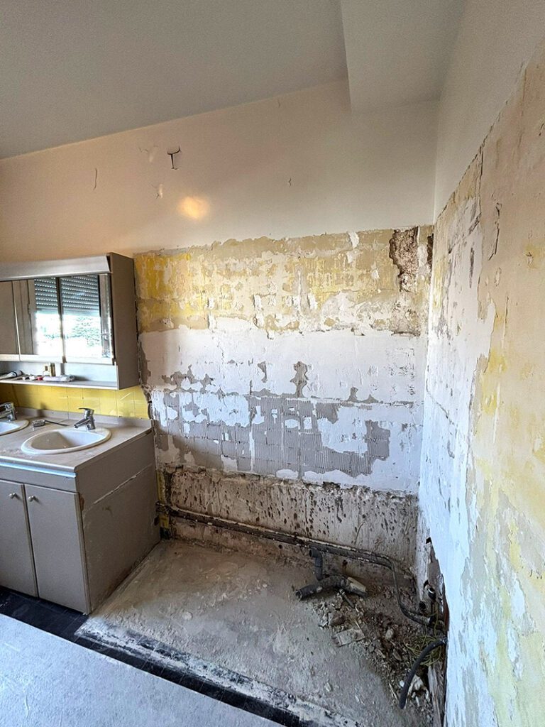 Salle de bain de 6m² pendant les travaux, avec carrelage mural et équipements démolis