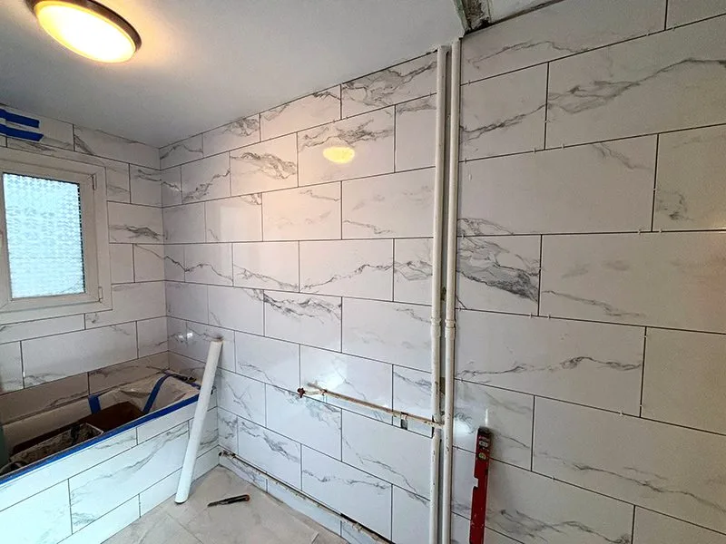 Travaux de carrelage en cours avec des carreaux blancs pour maximiser la lumière
