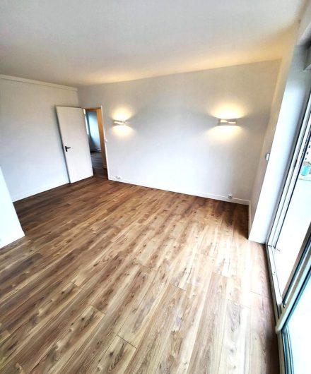 Salon d’appartement rénové avec parquet stratifié et murs repeints