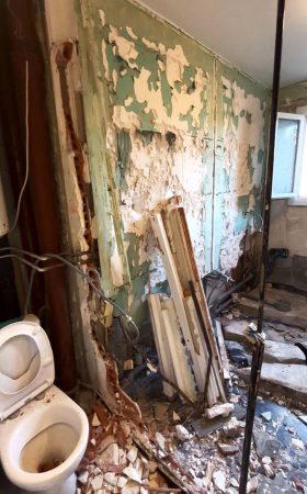 Première vue de la salle de bain avant rénovation, avec douche et cloison séparant les WC